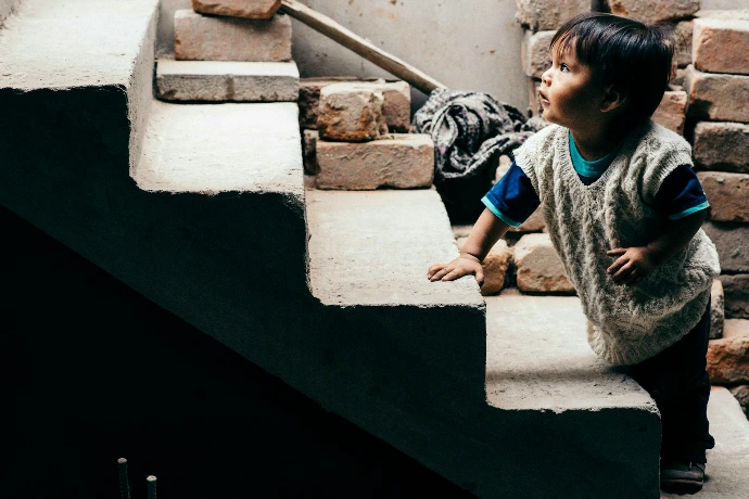 boy in gray and black crew neck t-shirt sitting on white concrete stairs